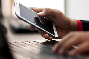 mobile hands holding cell phone using laptop